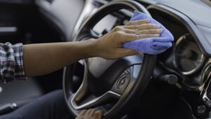 man clean dust on the dashboard of his car with cloth